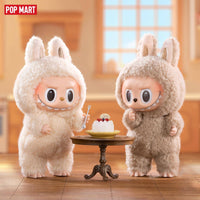POP MART The Monsters Tasty Macarons Blind Box Figures feature two fluffy bunny-suited vinyl toys standing by a dessert table with a macaron cake.