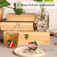 OTOTO Tea Trap infuser displayed in a cozy setting with books and plants. A whimsical tea gadget for enhancing tea time.