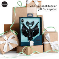 OTOTO Vino Spooky Bat Opener in gift box surrounded by wrapped presents. A spook-tacular gift idea for wine and beer enthusiasts.