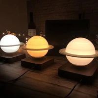 Set of three levitating Saturn lamps in different light modes: cold white, warm white, and warm yellow, on wooden bases.