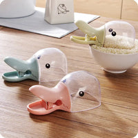 Duck-shaped pet food spoons in pastel colors, featuring a clip design for easy food scooping and sealing, placed on a wooden table.