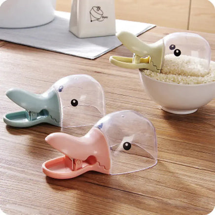 Duck-shaped pet food spoons in pastel colors, featuring a clip design for easy food scooping and sealing, placed on a wooden table.