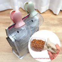 Pet Food Spoon with clip feature for sealing pet food bags, crafted from durable plastic, shown in pink and green colors.