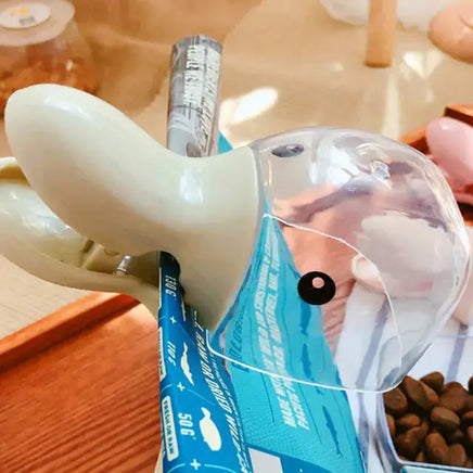 Pet Food Spoon with a built-in clip attached to a pet food bag, featuring a transparent scoop and durable plastic design for easy mealtime.