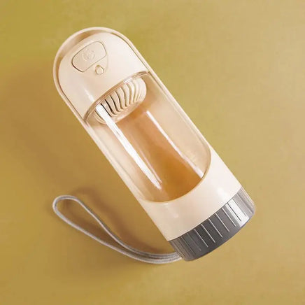 Portable pet water bottle feeder for dogs with a beige design, featuring a built-in drinking bowl and wrist strap for travel convenience.