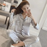 Women Silk Satin Pajamas in silver color featuring a button-down top with a chest pocket and matching pants. Perfect for luxurious comfort and relaxation.