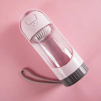 Portable pet water bottle feeder for dogs with a pink and gray design, featuring a built-in drinking bowl and wrist strap for travel convenience.