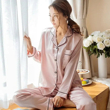 Women Silk Satin Pajamas in soft pink with black piping, featuring a button-up shirt and matching pants. Perfect for luxurious comfort and relaxation.