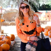 Stylish woman in Halloween Pumpkin Sweatshirt - Perfect for Spooky Season, accessorized with scarf and tote bag at a pumpkin patch.