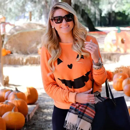 Stylish woman in Halloween Pumpkin Sweatshirt - Perfect for Spooky Season, accessorized with scarf and tote bag at a pumpkin patch.