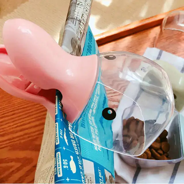 Pink pet food spoon with a built-in clip for sealing food bags, simplifying mealtime and storage for pets. Made of durable plastic.