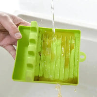 Green spatula drain rack gadget being rinsed under running water, showcasing easy cleaning functionality.