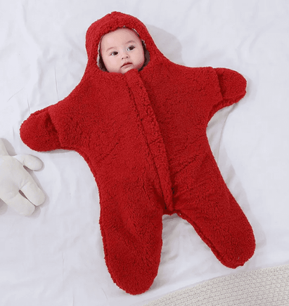 Baby in red fleece hooded onesie on white bedding