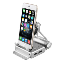 Silver podium style stand holding a smartphone, highlighting its compact design, USB ports, and adjustable angles.