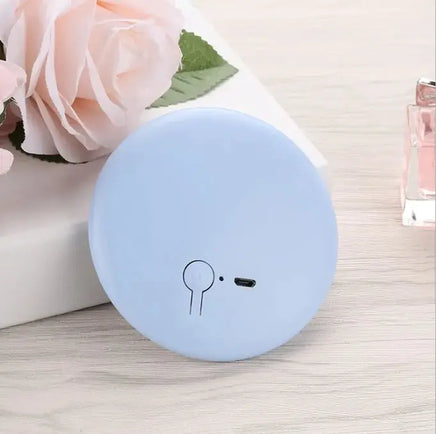 Pastel blue Pocket LED Makeup Mirror displayed on a table with flowers, emphasizing its sleek and portable design.