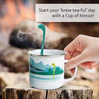 Cute Tea Infuser by OTOTO shaped like Nessie in a white enamel mug with mountain design, ideal for loose leaf tea brewing and fun kitchen gifting.