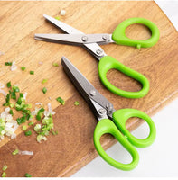 Two multifunctional green onion scissors with green handles placed on a wooden cutting board next to chopped green onions.