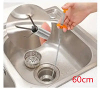 Orange-handled sewer dredger tool cleaning a kitchen sink drain, featuring a claw mechanism for effective clog removal.