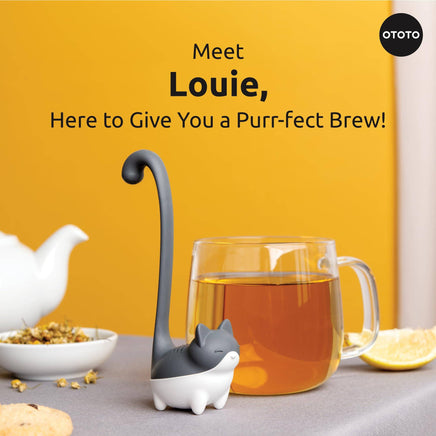 Cute Tea Infuser by OTOTO shaped like a cat named Louie, placed beside a glass mug of tea and teapot, ideal for loose leaf brewing.