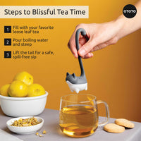 Cute Tea Infuser by OTOTO shaped like a cat tail, steeping loose leaf tea in a glass mug. Fun tea accessory ideal for flavorful tea moments.