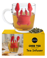 Cute Tea Infuser by OTOTO shaped like a red crab, hanging on a glass mug filled with tea. Fun tea accessory perfect for loose leaf tea lovers.