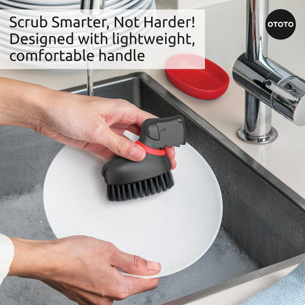 Oscar Dog Dish Brush by Ototo shown wet after use, resting in its red tray, perfect for scrubbing dishes and vegetables.