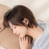 Woman sleeping on her side wearing a small, ergonomic Bluetooth earbud designed for comfort and long-term use.