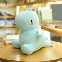 Light blue dinosaur plush toy sitting on a wooden table in a library-like setting, surrounded by bookshelves.