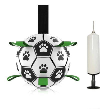 Black and white dog football toy with paw print design and green straps, accompanied by a white pump.