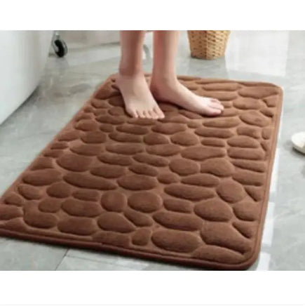 Brown super absorbent shower room floor mat with a pebble-like texture, shown with a person standing on it.