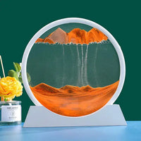 Moving Sand Art Picture Frame featuring black sand forming dynamic landscapes in a circular frame with a white base, set against a green background.