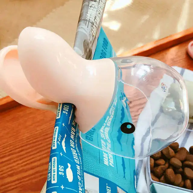 Pet Food Spoon with a clip design attached to a pet food bag, made of durable plastic for easy scooping and sealing.
