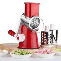 Red vegetable cutter kitchen gadget with rotary grater and interchangeable blades, surrounded by sliced vegetables in bowls.