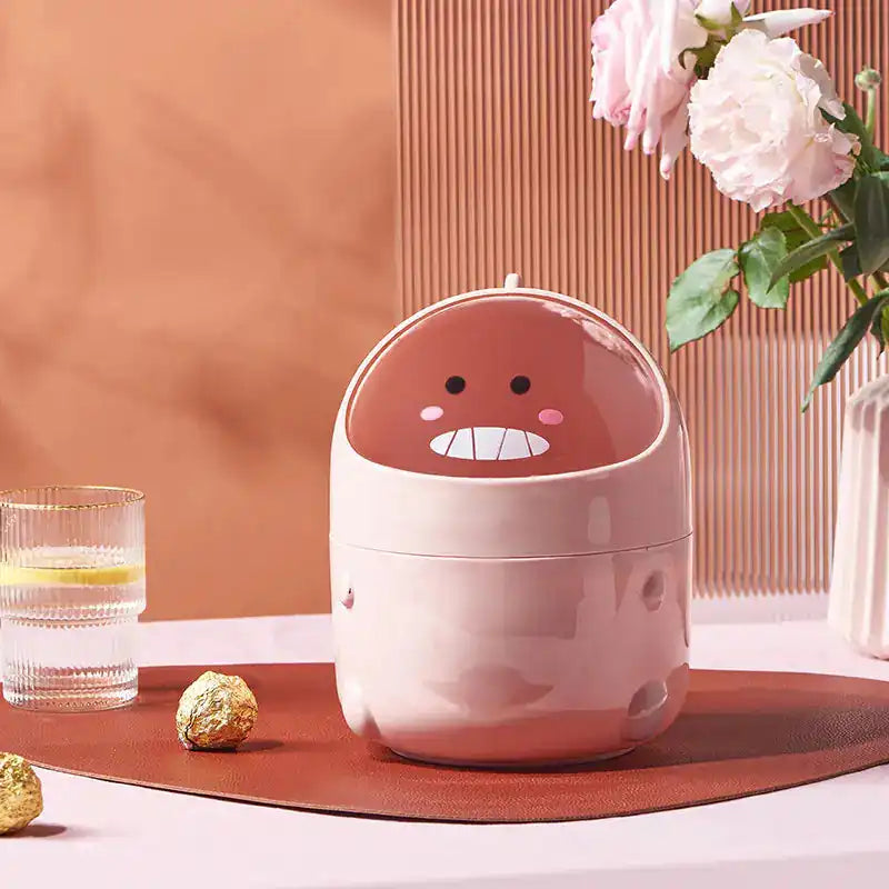 Pink dinosaur desktop trash can placed on a desk with flowers and decor, combining fun design with practical home office use.