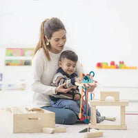 Mother and child playing with a sensory toy featuring vibrant pull strings, fostering sensory stimulation and coordination.