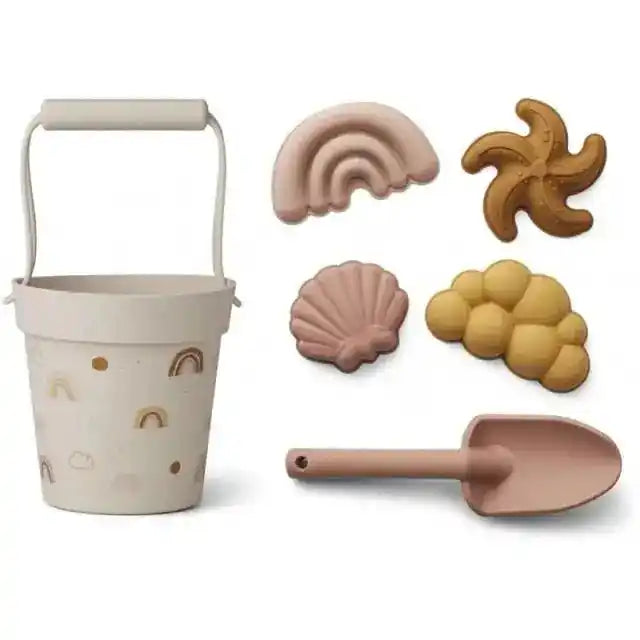 Rainbow-themed beach toy set with a white bucket decorated with rainbows, a matching shovel, and sand molds for creative play.