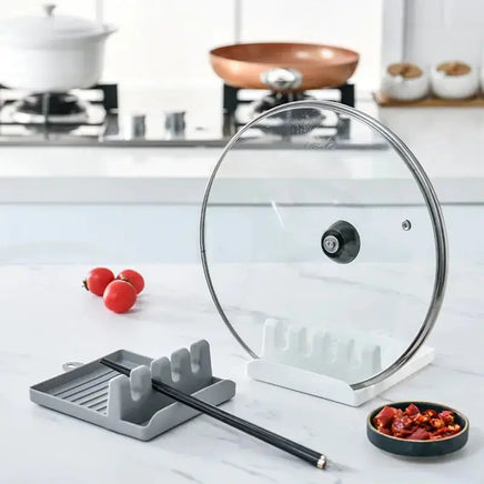 Gray spatula drain rack gadget holding a pot lid and chopsticks, ideal for keeping kitchen counters clean.