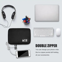 Black gadget organizer bag on a desk with a laptop, headphones, and phone, showcasing its double zipper feature.