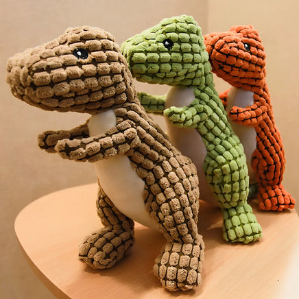 Set of three dinosaur plush dog toys in brown, green, and orange, designed for fun and durable pet entertainment.