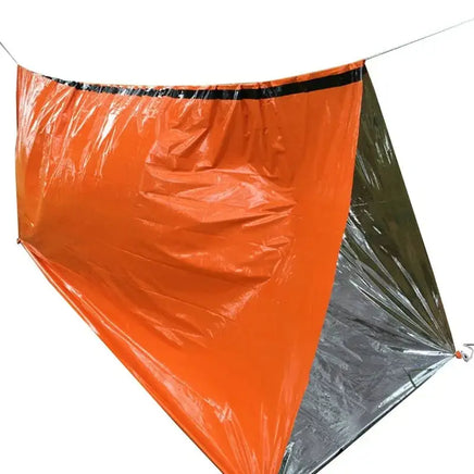 Emergency sleeping bag used as a makeshift shelter, featuring a reflective silver interior and durable orange exterior.