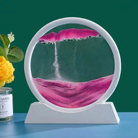 Moving Sand Art Picture Frame with orange sand creating vibrant patterns in a circular frame with a white base, placed against a green background.