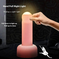 Hand pulling a pink small night lamp to activate its soft glow, showcasing its creative design and functionality for ambient lighting.