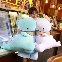 Woman holding two large dinosaur plush toys, one blue and one pink, in a cheerful café environment.