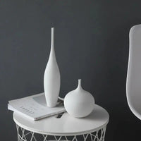 Two white Jingdezhen modern minimalist handmade vases on a round white table, paired with books and a modern chair.