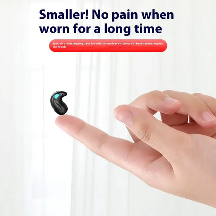 Compact black Bluetooth earbud resting on a fingertip, designed for side sleeping with skin-friendly silicone for long-term comfort.