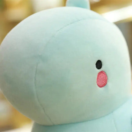 Close-up of a light blue dinosaur plush toy showcasing its soft fabric and embroidered pink cheeks.