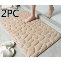 Beige super absorbent shower room floor mat with a pebble-like texture, sold as a 2-piece set, placed near a shower area.