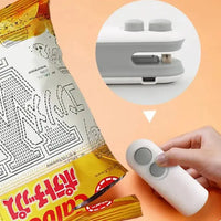 White handheld vacuum sealing machine sealing a chip bag, showcasing its USB rechargeable feature for food preservation.