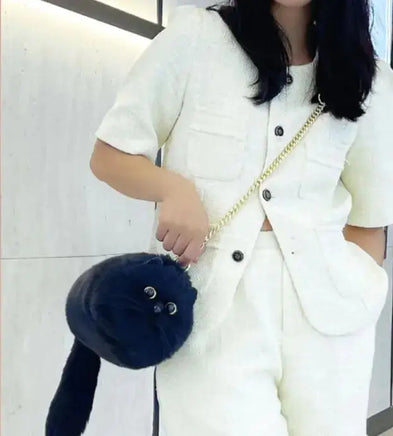 Woman carrying a black handmade plush cat messenger bag with a gold chain strap, showcasing a fun and unique accessory for casual outfits.