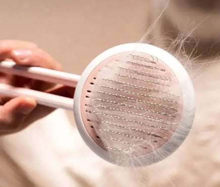 Close-up of pink Automatic Hair Remover & Massage Comb removing pet hair, showcasing its effective grooming bristles.